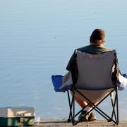 person sitting in folding chair looking at lake