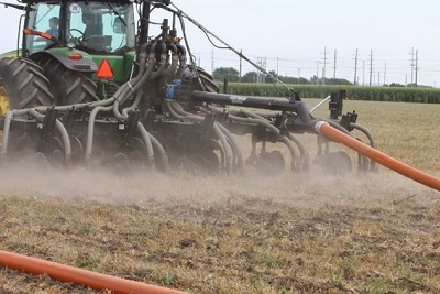 A tractor pulling a drag-hose toolbar.