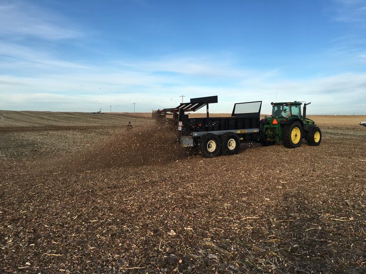 photo of spreading cedar mulch and manure with manure spreader and tractor