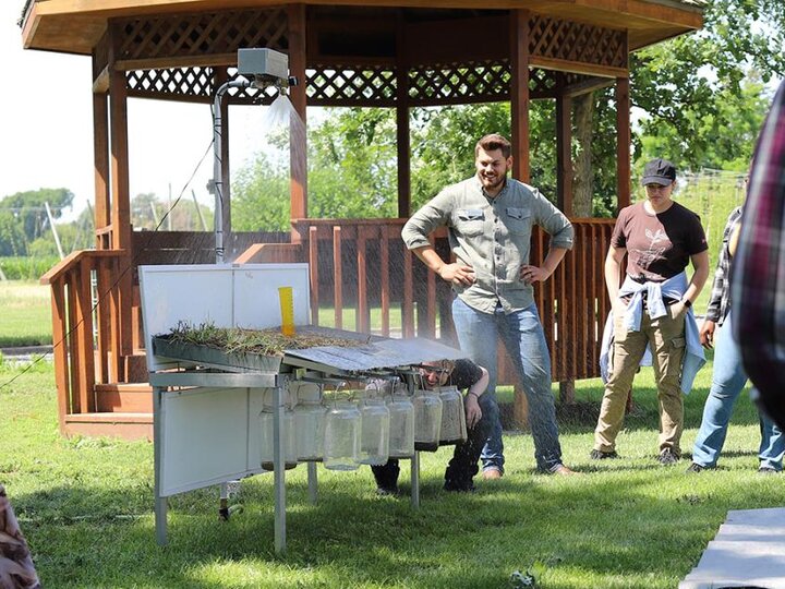 man stands near rainfall simulator during presentation