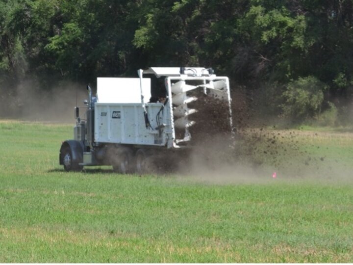 Typical manure spreader broadcasting manure solid to soil as fertilizer amendment.