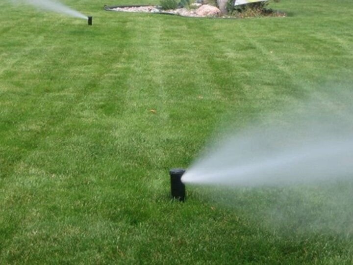 Irrigation heads on the lawn projecting water blowing out of the irrigation system. 