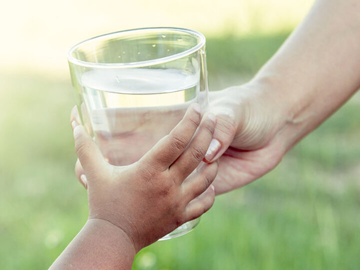 Child's hand holding a glass of water.