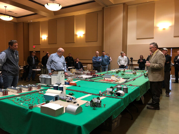People looking at a model of an animal feeding operation