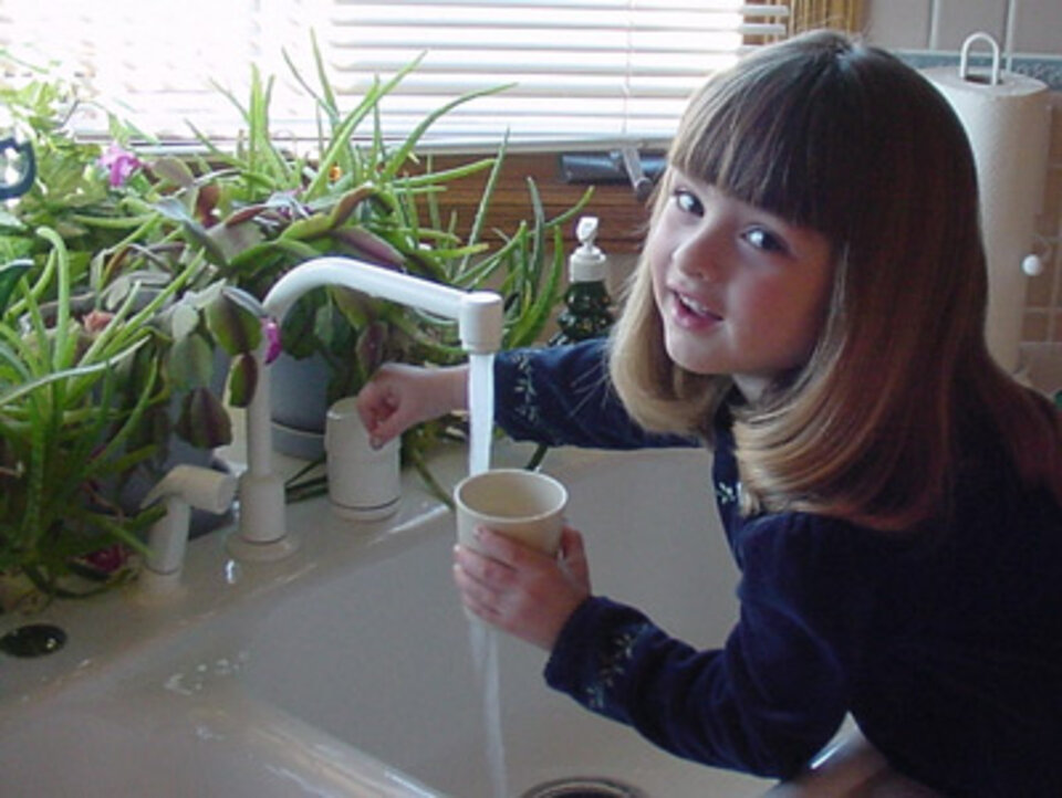 Girl getting a drink of water from the sink